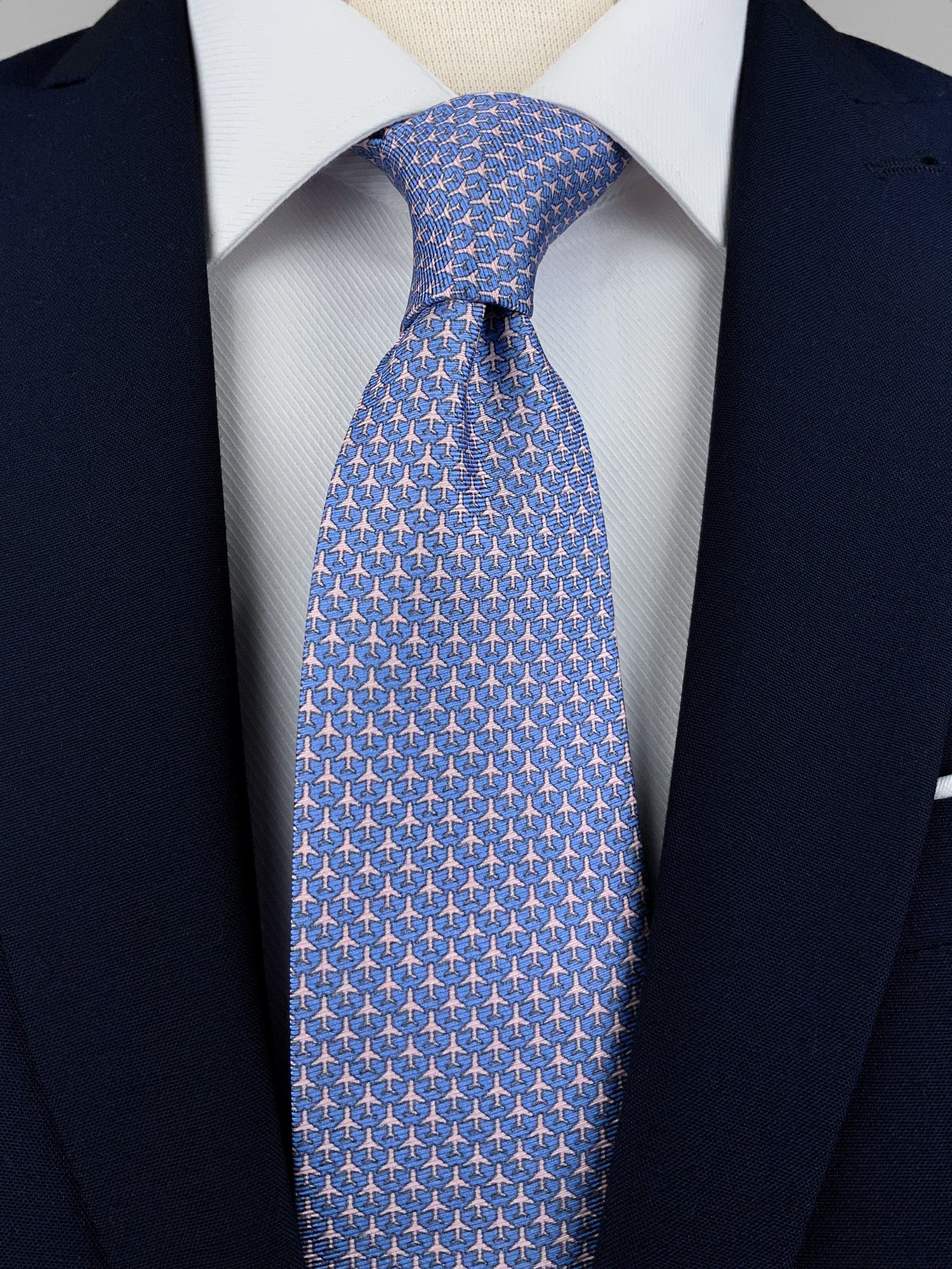 Light blue mulberry silk twill tie with a airplane microprint pattern in a pink shade worn with a white shirt and a navy blue suit