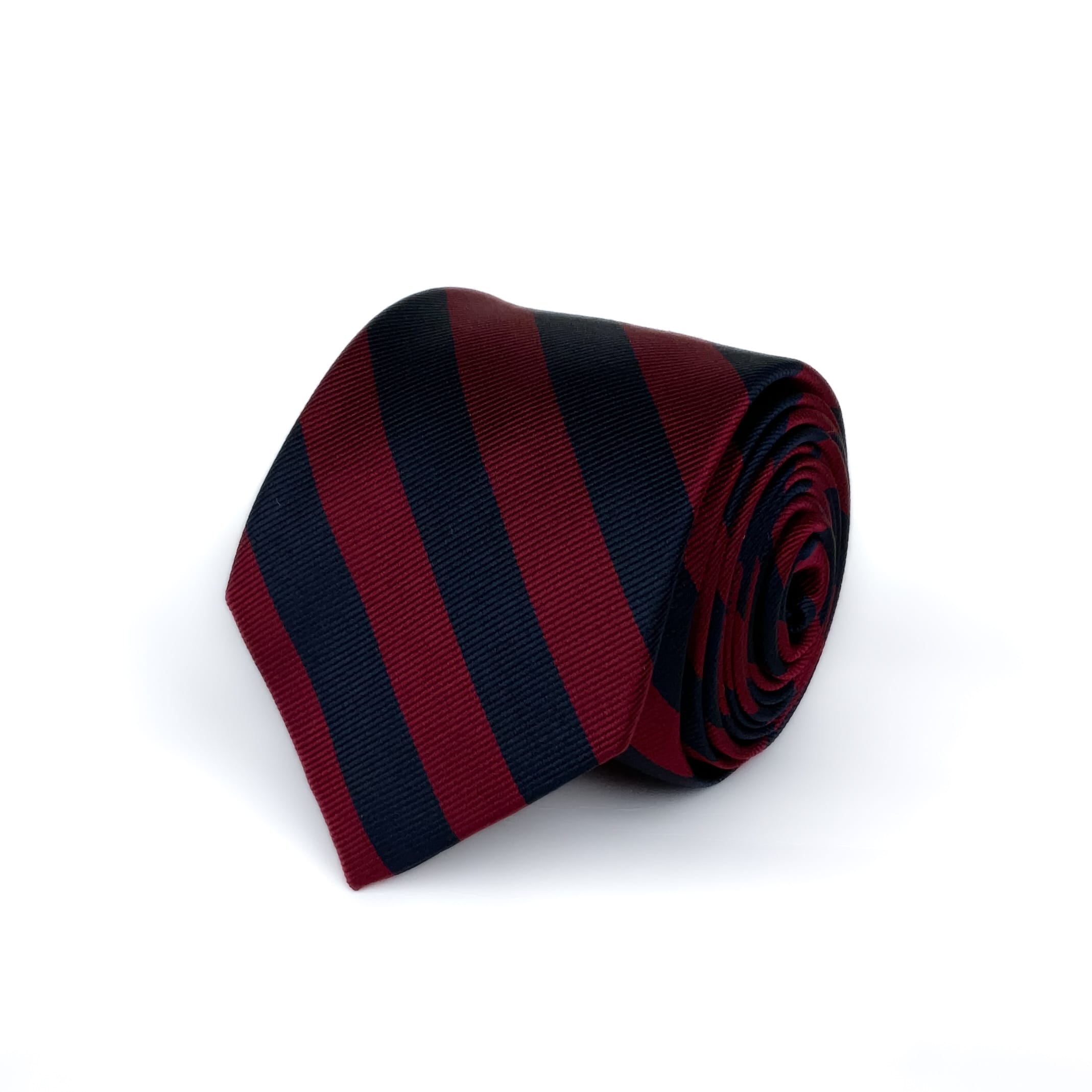 Red and Navy Blue Striped Silk Regimental tie rolled an placed on a white background