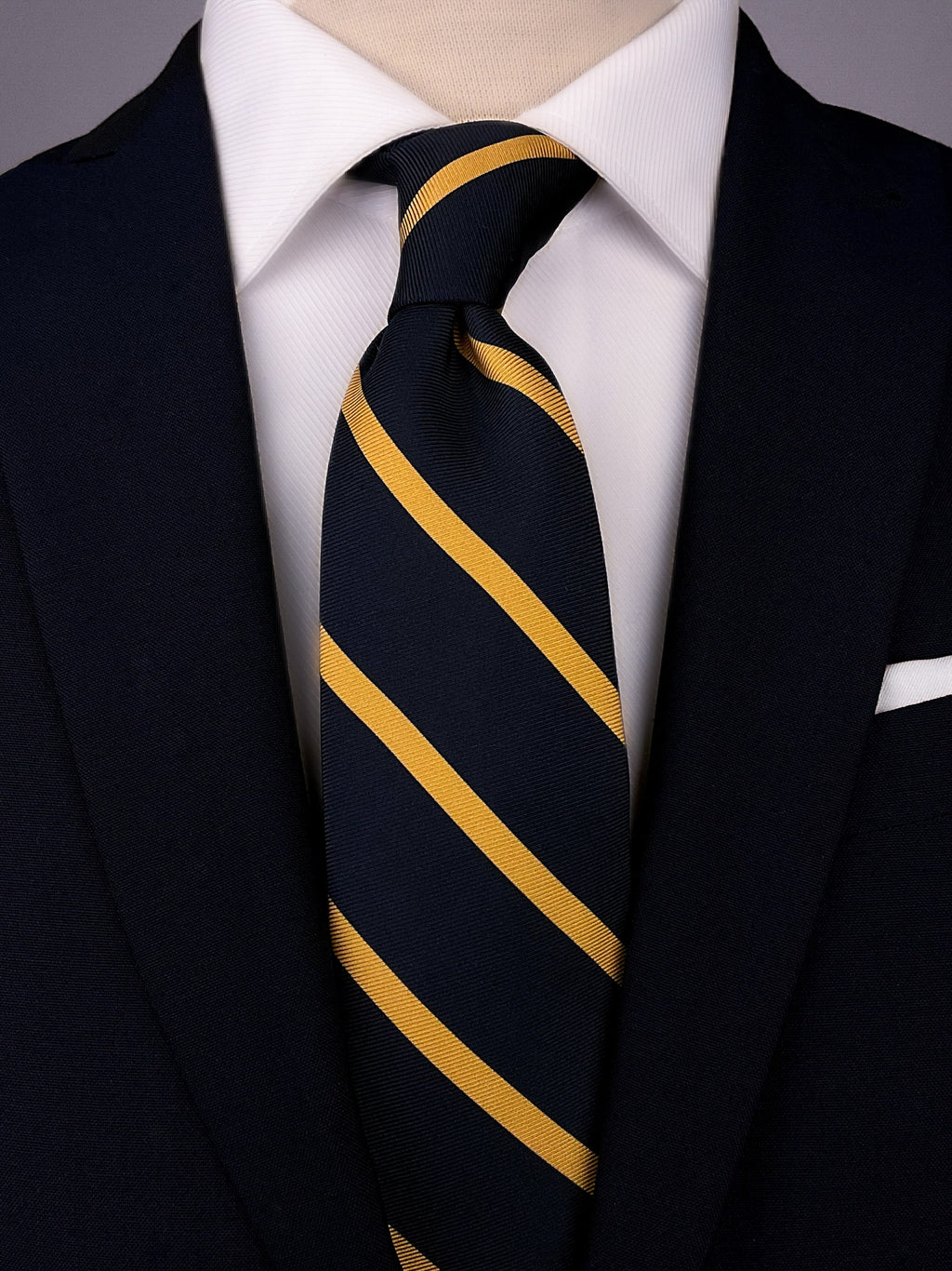 Navy blue and yellow striped silk Regimental tie worn with a white shirt and a navy blue suit.