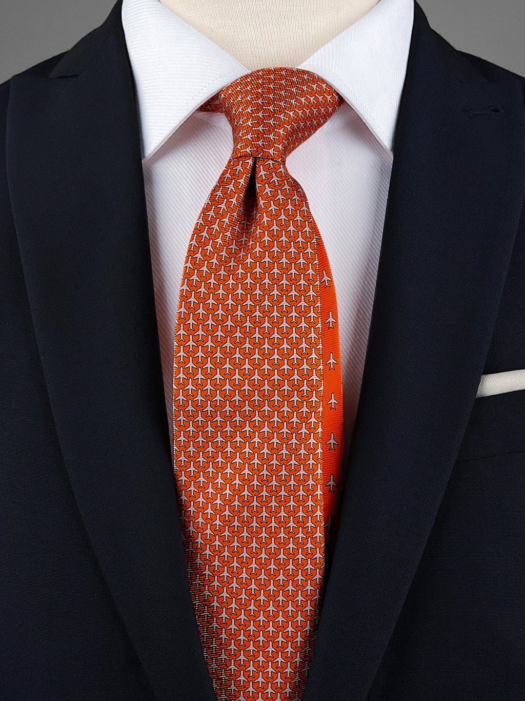 Orange mulberry silk twill tie with a airplane microprint pattern in a pink shade worn with a white shirt and a navy blue suit