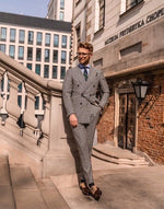 Man wearing a grey prince of Wales check suit with a green and navy blue striped regimental necktie