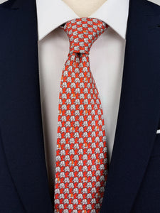 Bright red mulberry silk twill tie with a grey micro-pattern of elephants printed on top worn with a white shirt and navy blue suit