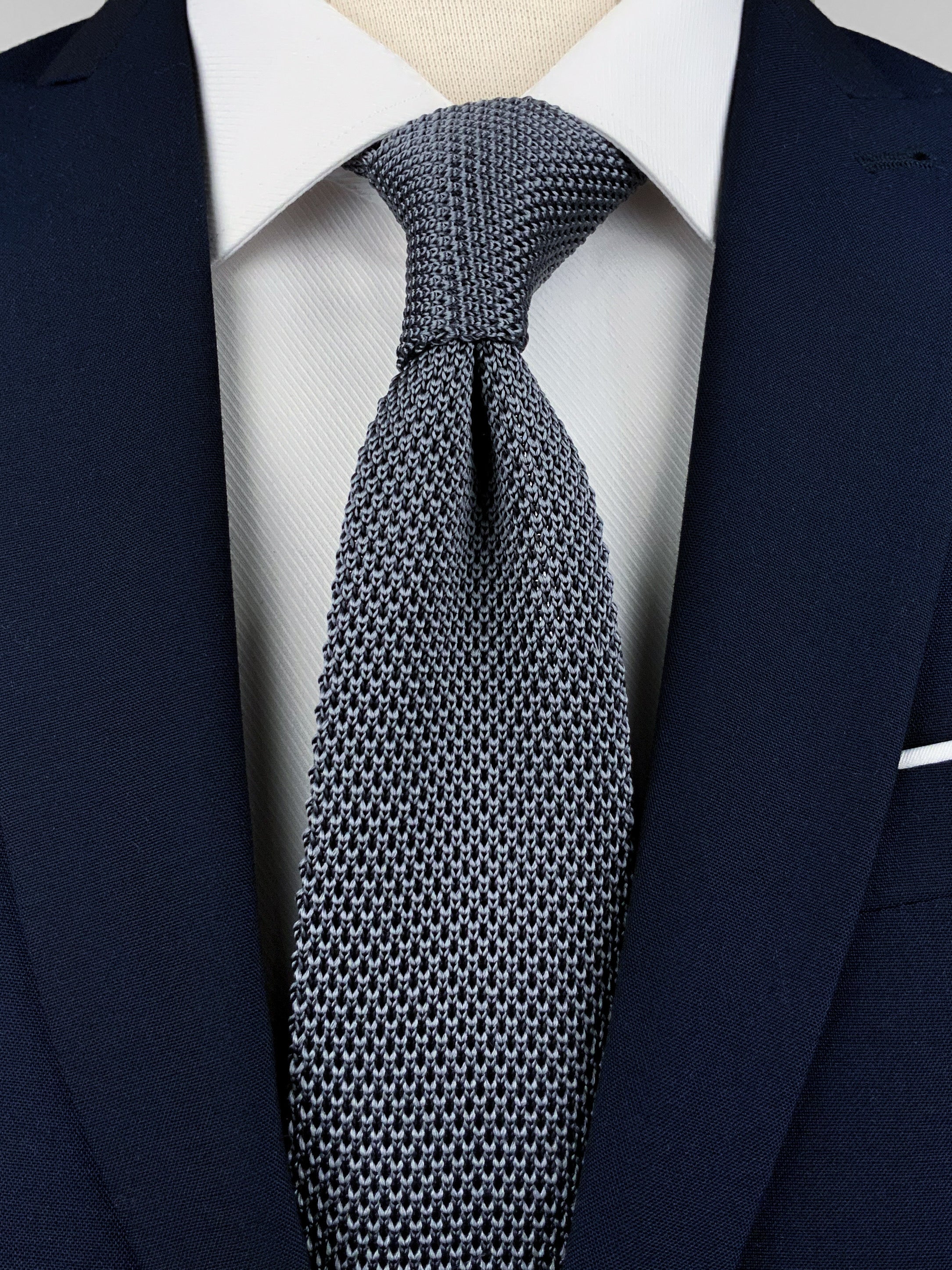 Dark grey mulberry silk knitted tie worn with a white shirt and a navy blue suit
