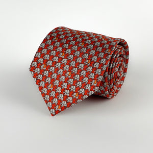 Bright red mulberry silk twill tie with a grey micro-pattern of elephants printed on top rolled and placed on a white background
