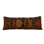 Antique Kilim rug cushion with a brown base color and with multicolored geometric pattern. The cushion is long and rectangular in shape.
