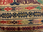 An antique kilim rug cushion with a brown base and a multicolored geometric pattern.