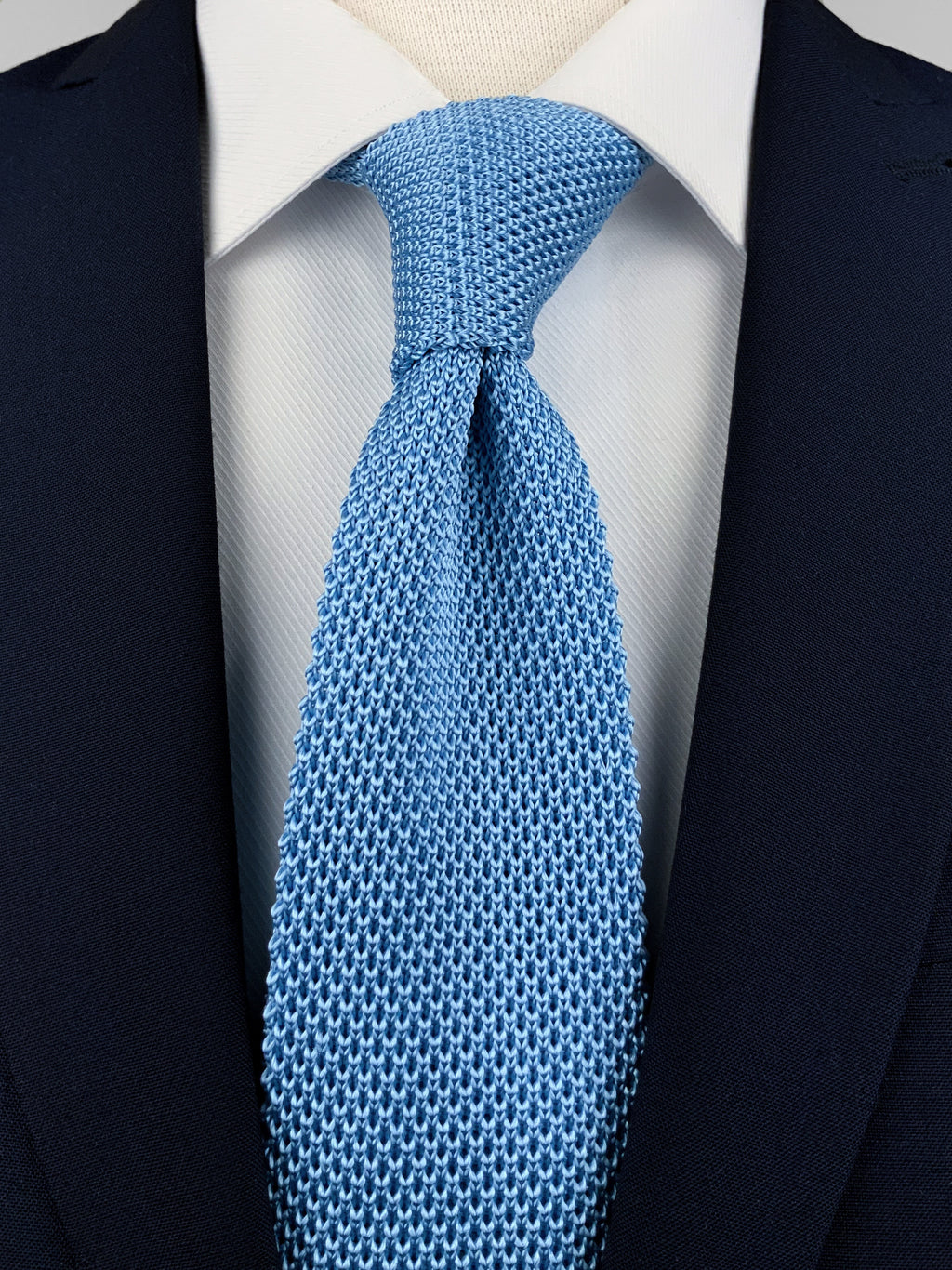 Sky blue mulberry silk knitted tie worn with a white shirt and a navy blue suit