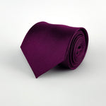 dark purple mulberry silk satin tie rolled and placed on a white background