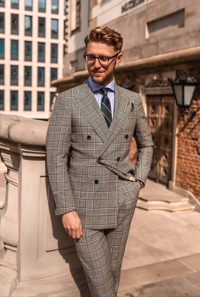 Man wearing a grey prince of Wales check suit with a green and navy blue striped regimental necktie