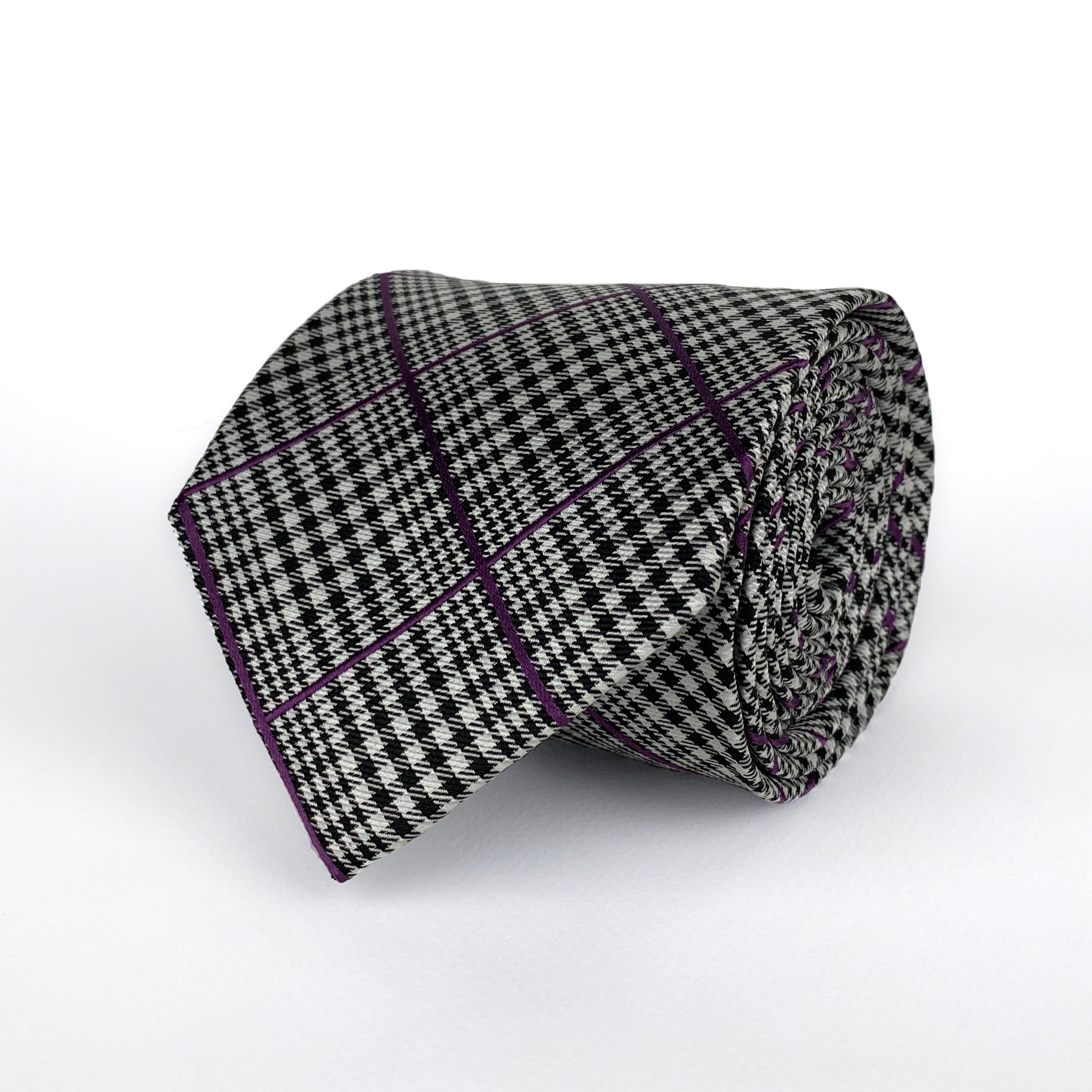 Prince of Wales Check, also known as Glen Plaid, silk twill tie in black and white with woven detailing in a purple hue rolled and placed on a white background