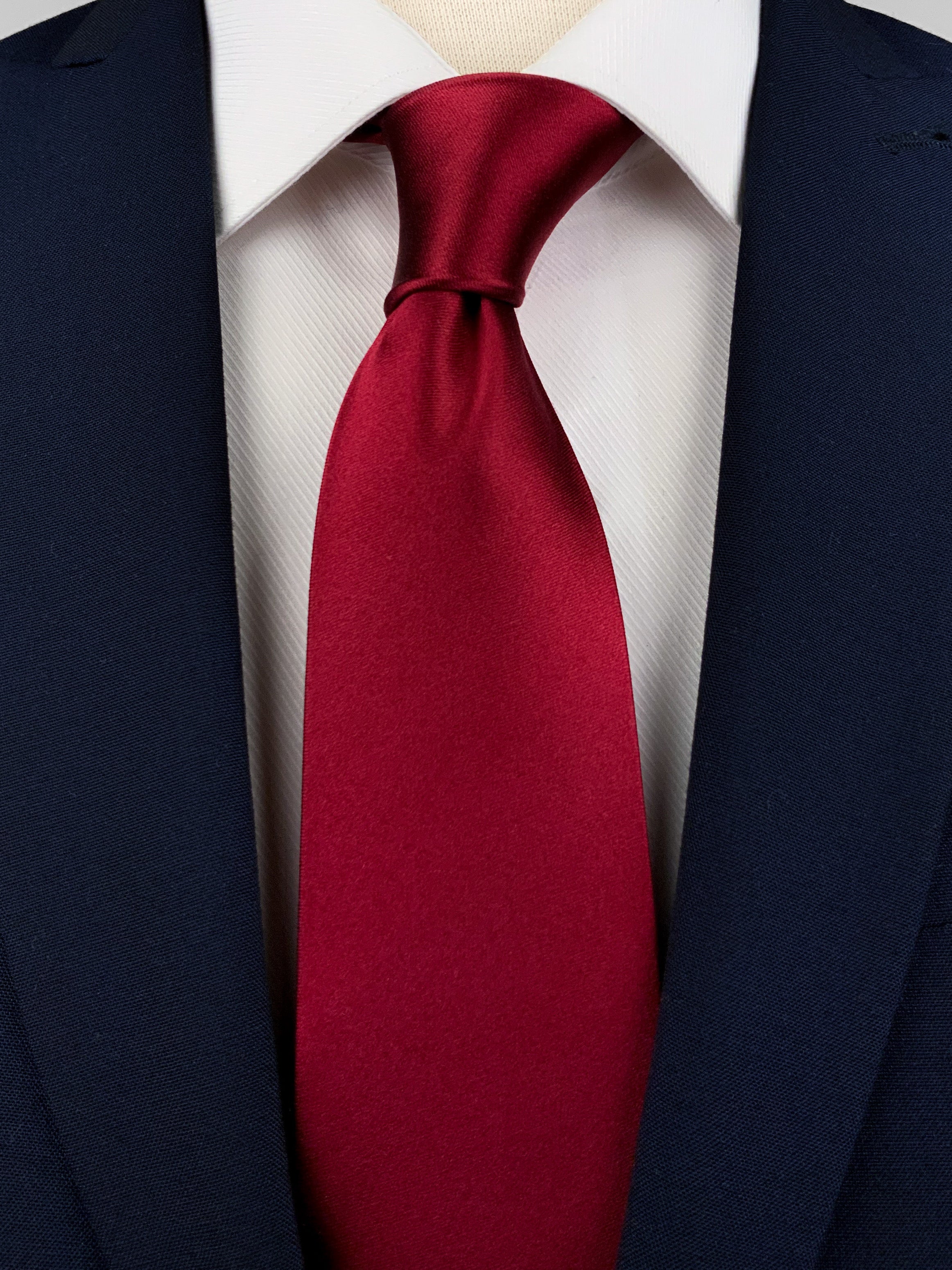 Dark red mulberry silk satin tie worn with a white formal shirt and navy blue suit