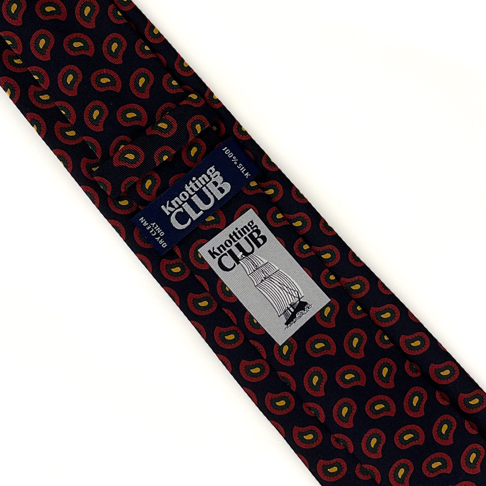 The back side of a paisley tie with a black base and red and yellow motifs. The label and logo of the brand are also visible.