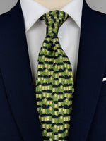 Mulberry silk twill tie printed with a pattern of houses in a green color with black roofs and yellow windows worn with a white shirt and navy blue suit 