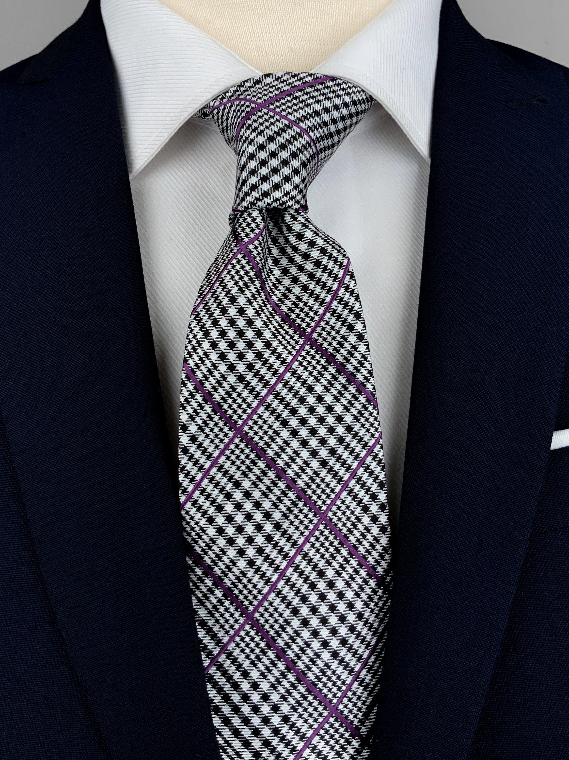 Prince of Wales Check, also known as Glen Plaid, silk twill tie in black and white with woven detailing on top in a purple hue worn with a white shirt and a navy suit