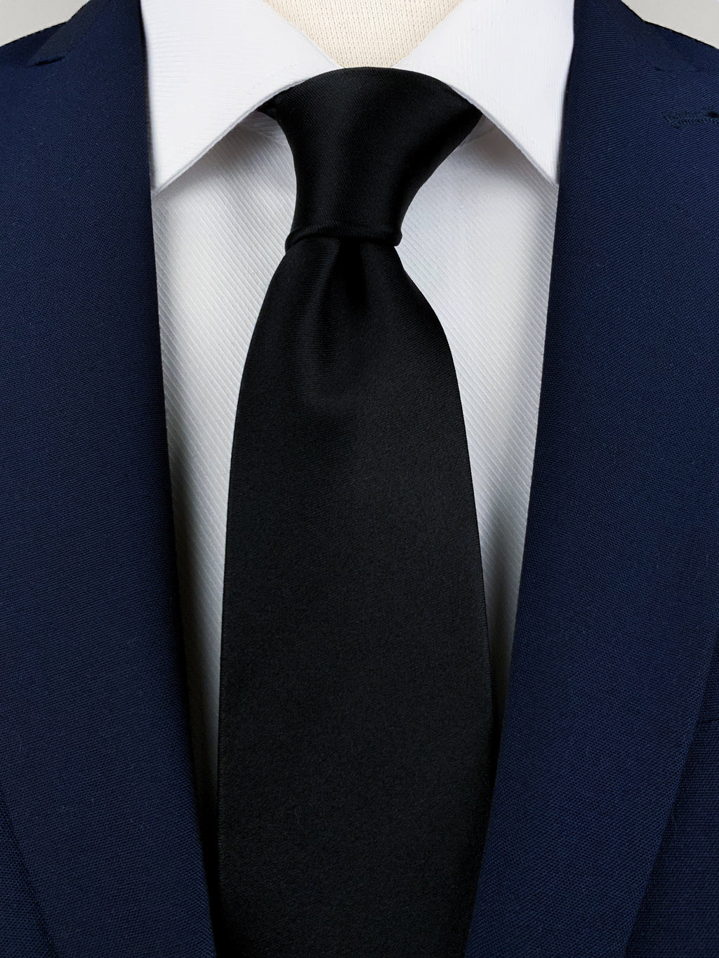 Black mulberry silk satin tie worn with a white shirt and a navy blue suit