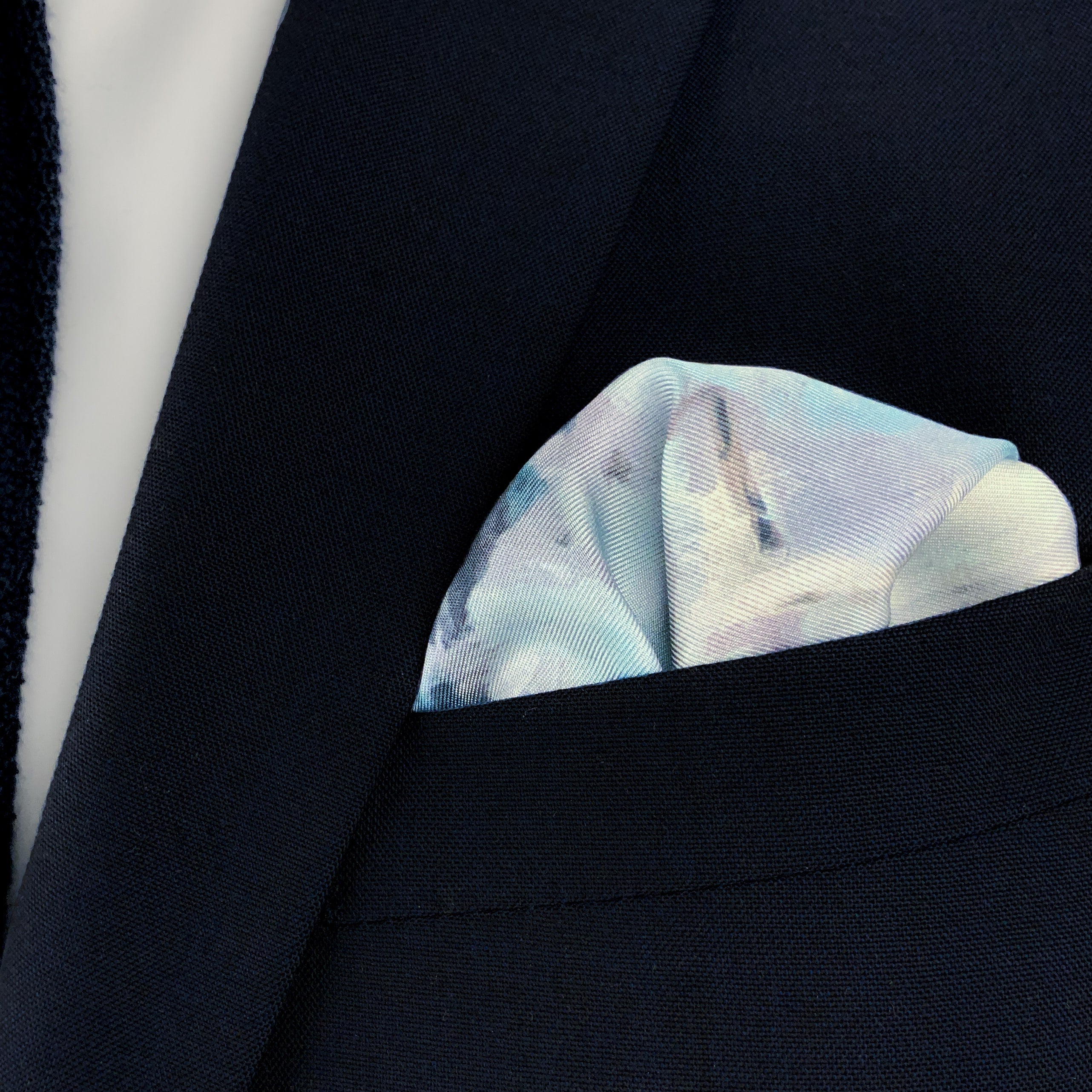 The Magpie historical fine art silk pocket square folded and placed in the breast pocket of a navy blue suit