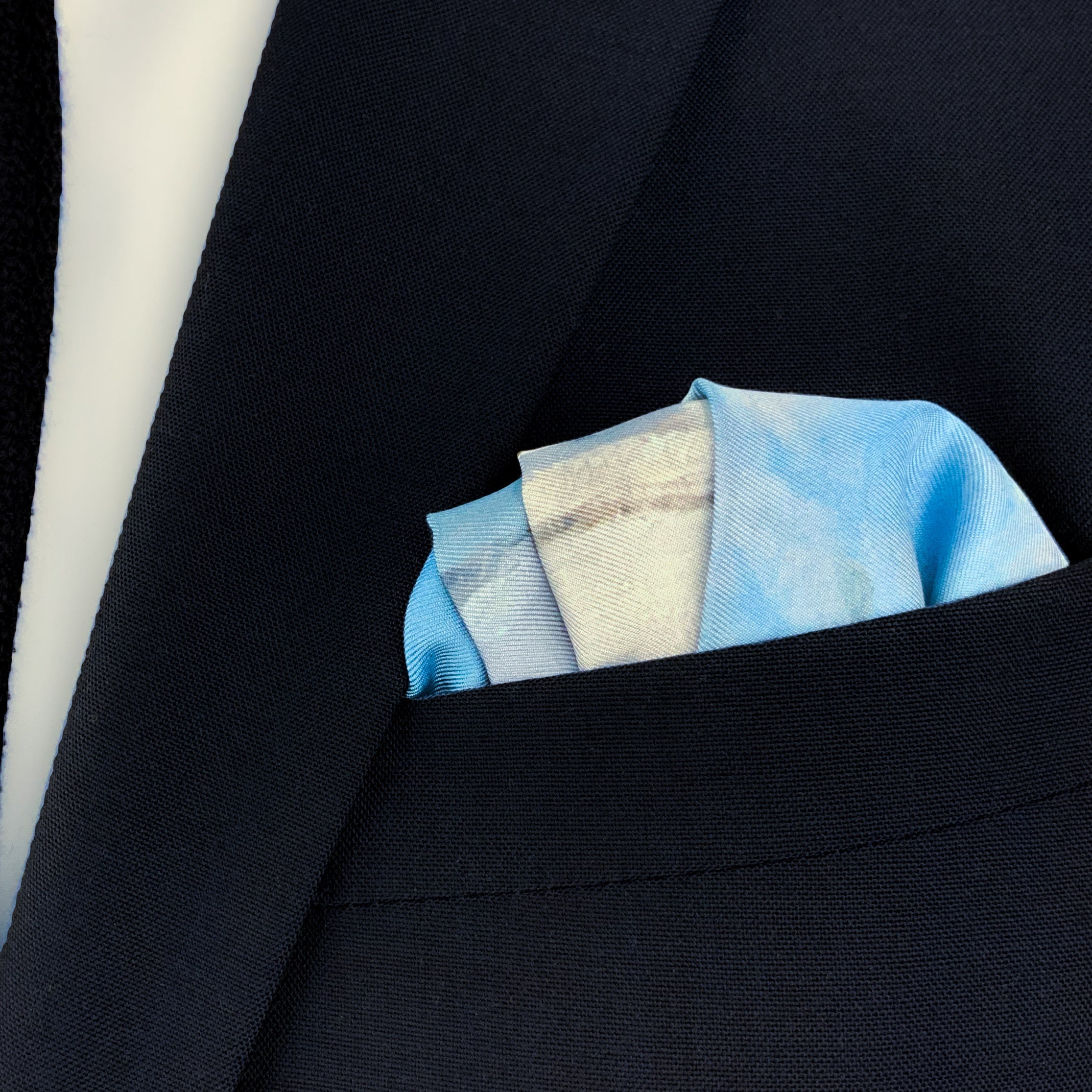 The Magpie historical fine art silk pocket square folded and placed in the breast pocket of a navy blue suit