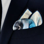 The Magpie historical fine art silk pocket square folded and placed in the breast pocket of a navy blue suit