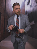 Man wearing a grey suit and a red and navy blue striped silk regimental necktie